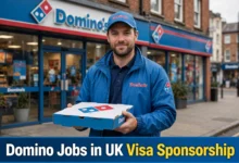 Domino Jobs in UK with Visa Sponsorship delivery driver holding pizza box in front of Domino's store